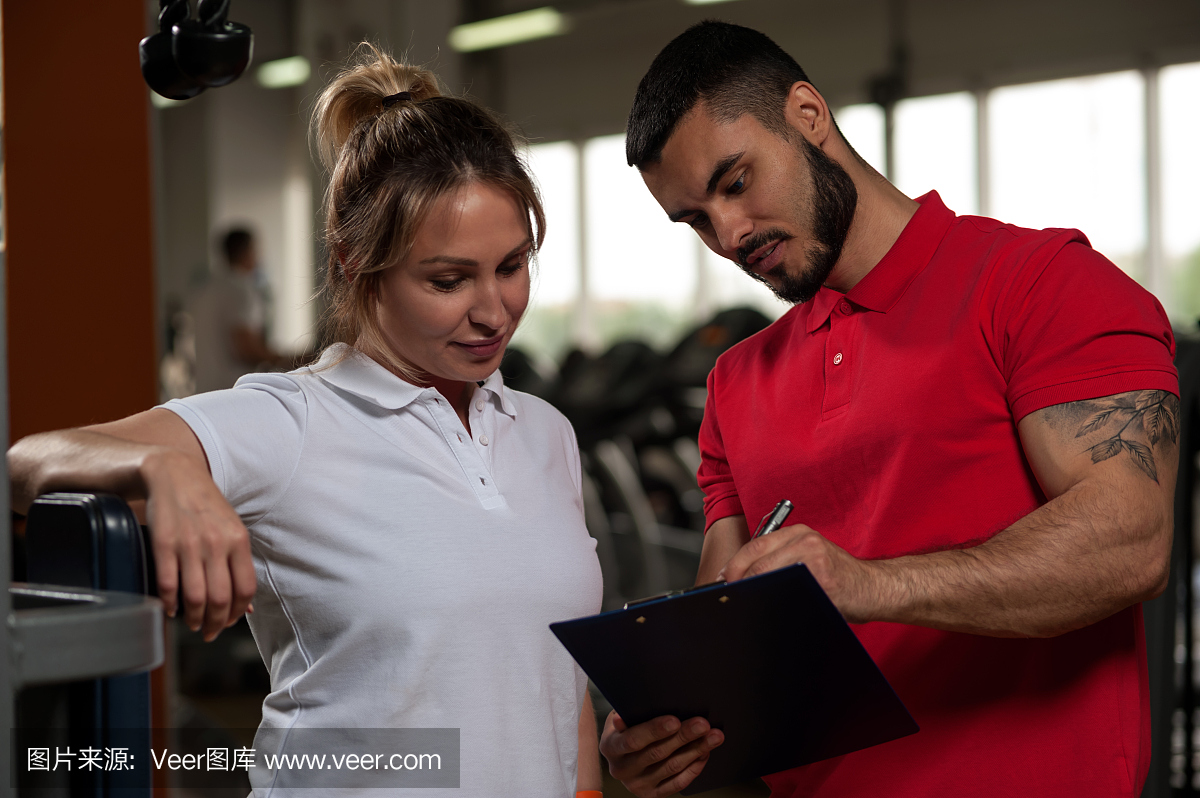 男性私人教练与女性客户端在健身房