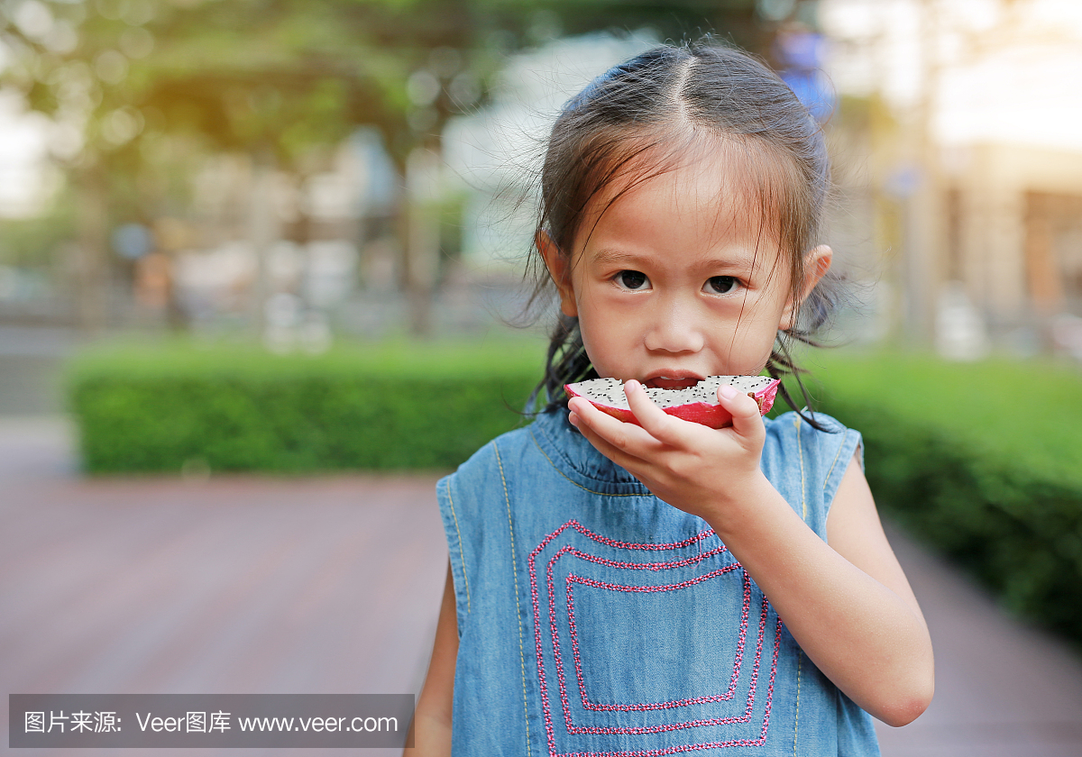 小女孩在公园里吃切片火龙果。