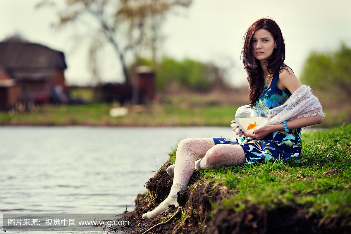 小女孩坐着一条带金鱼的池塘