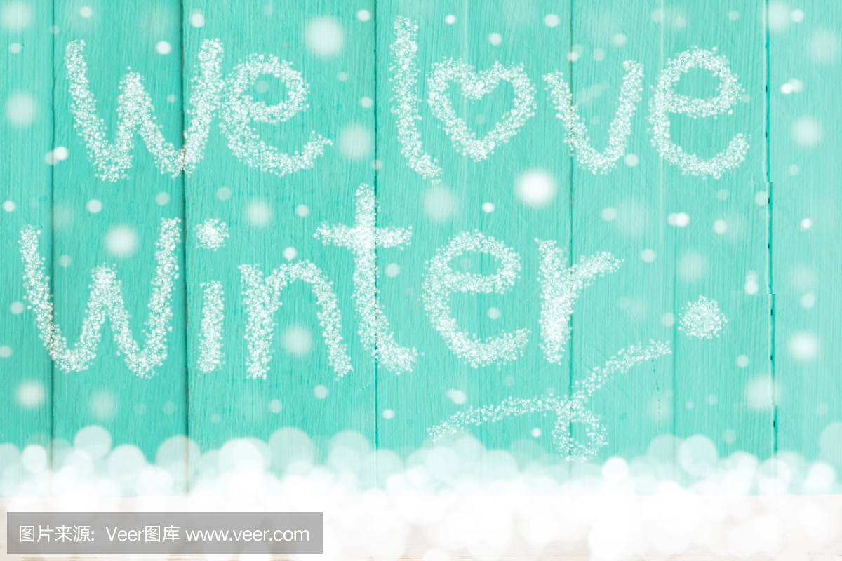 单词'我们爱冬天'与蓝色木背景上的降雪。用于