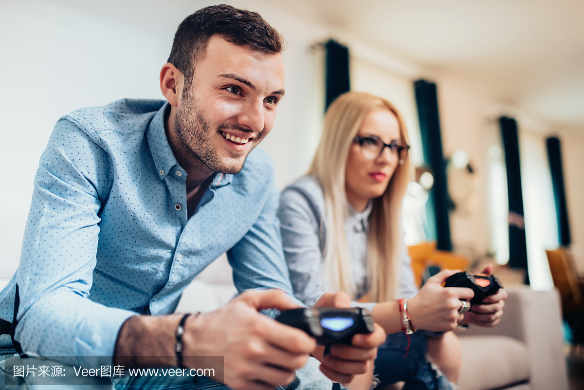 年轻夫妇享受电脑游戏与游戏机。现代生活方式