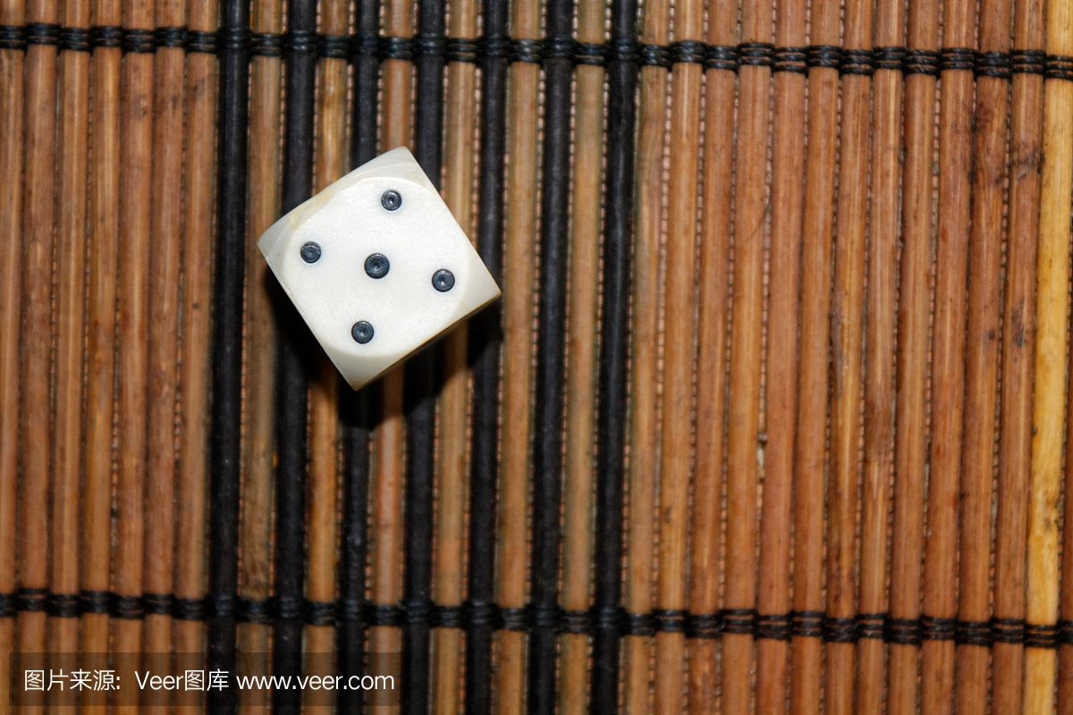 一个白色塑料骰子上棕色木板背景。黑色圆点的