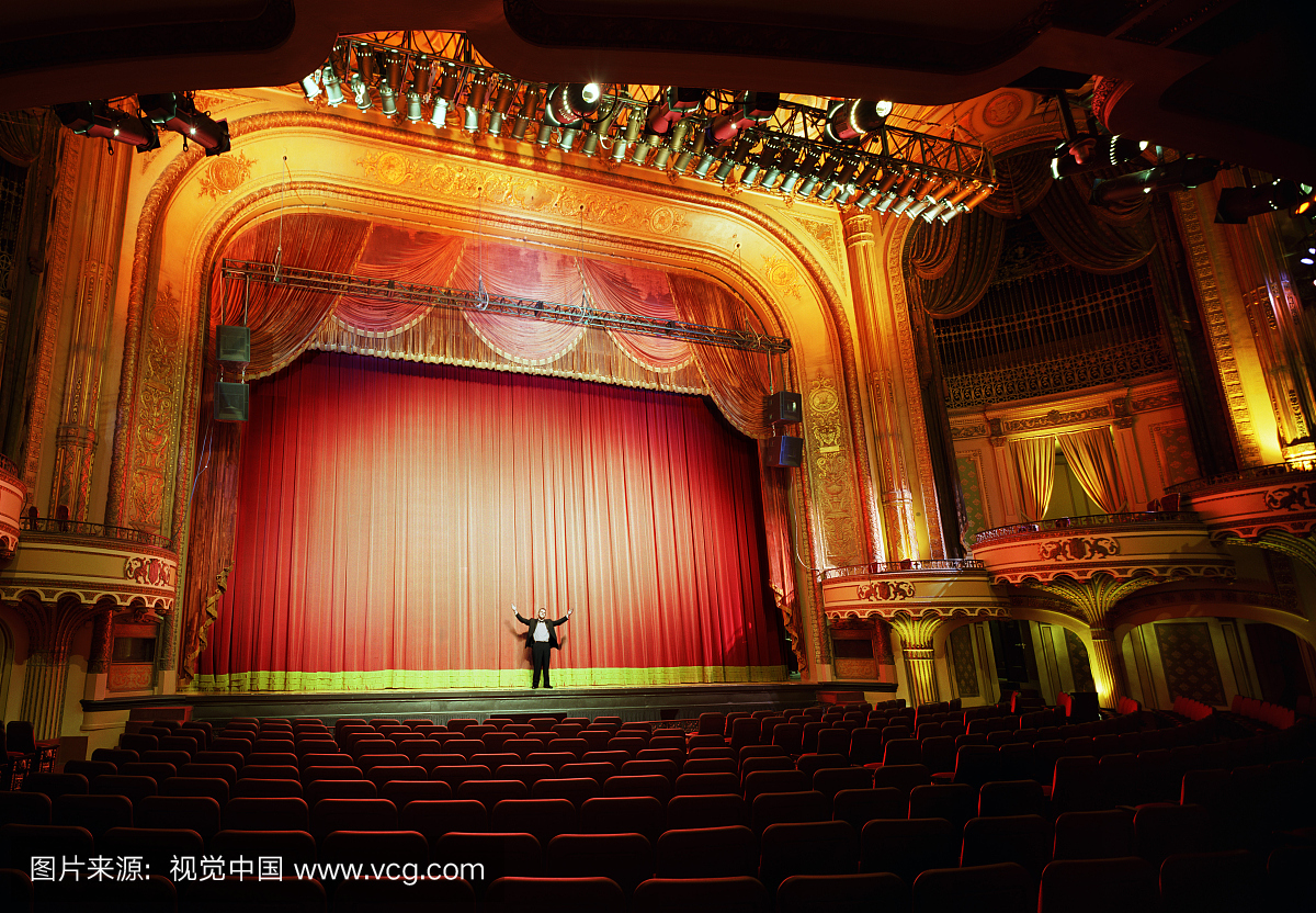 站在舞台上的人在空荡荡的剧院里伸出手臂