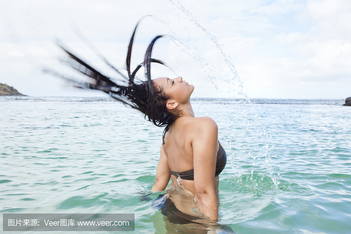 年轻女子在泻湖中翻转湿头发