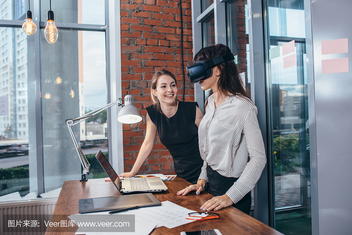 两名女学生在虚拟现实眼镜中玩3D游戏,在教室