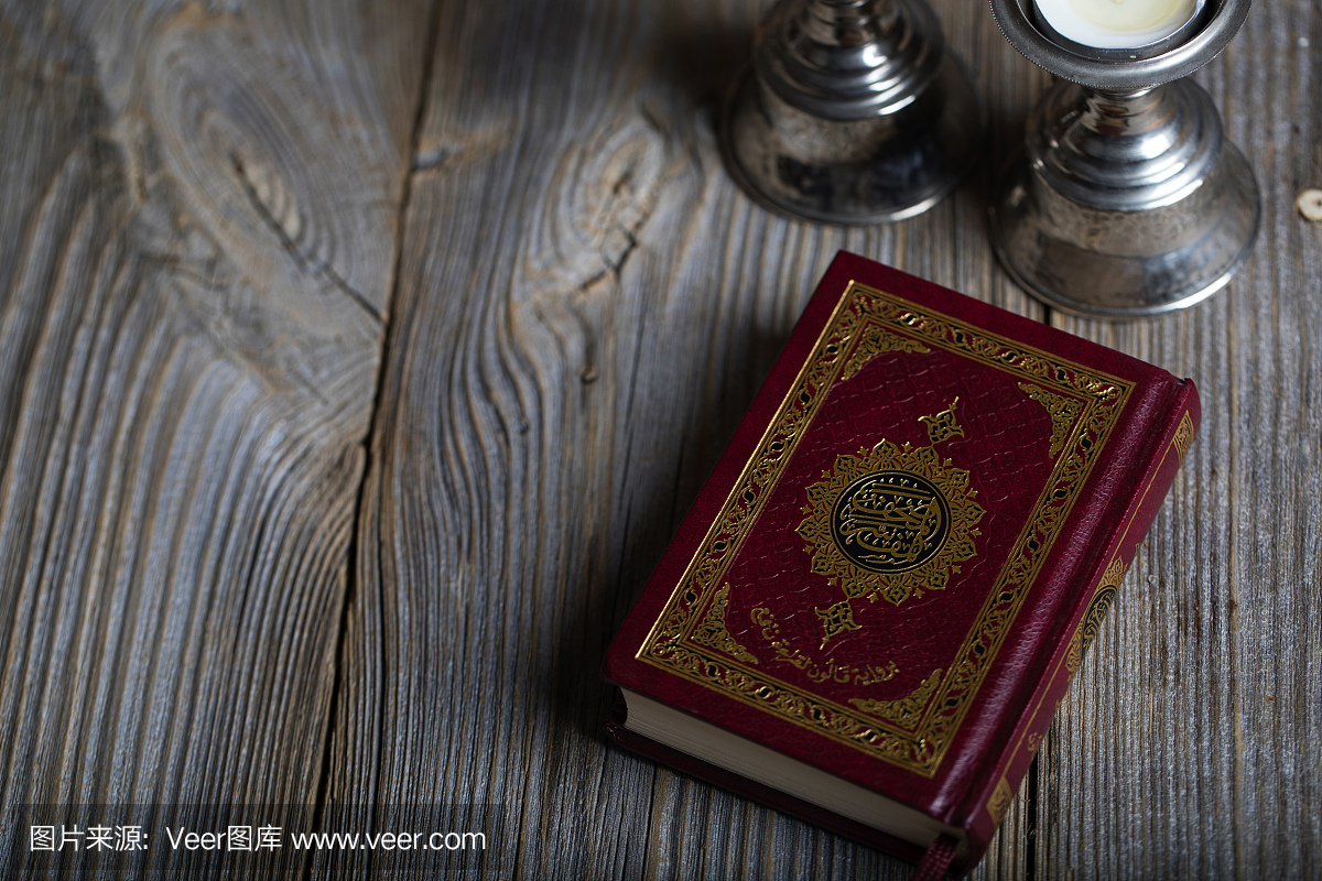 古兰经和木制表面上的蜡烛。翻译成英文 - 这本