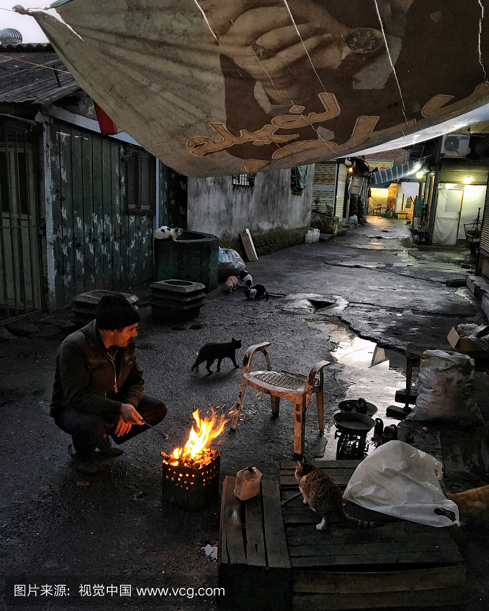 一名男子在拉什特大巴扎后面的一条小巷里用火
