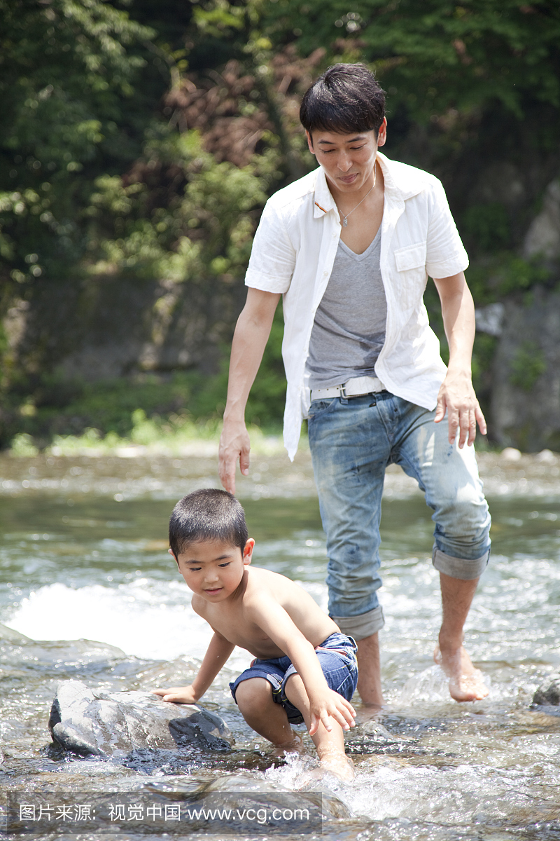 一个男孩和他的父亲在河里玩耍。