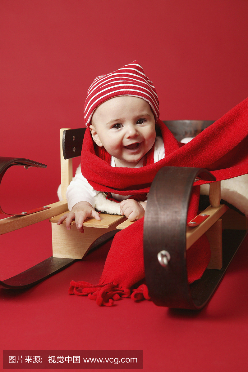 宝宝男孩(3至6个月)在玩具雪橇上,戴着圣诞围巾