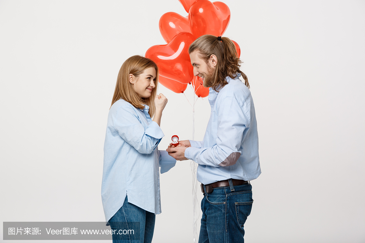 年轻帅哥的肖像给一个女孩带着红色的心形气球
