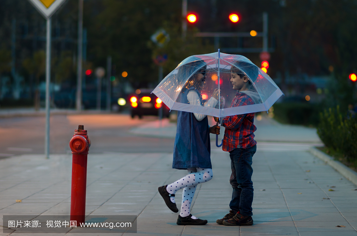 男孩和女孩在晚上的城市的伞