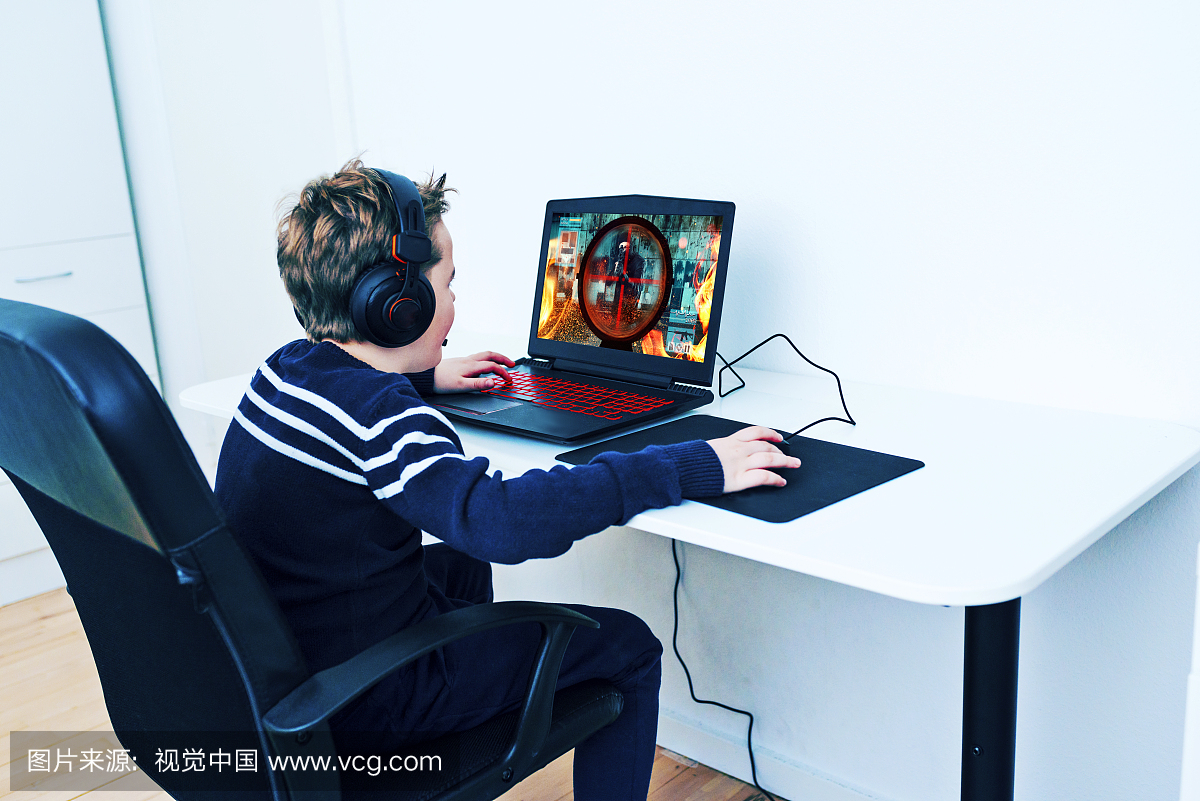 男孩坐在电脑前,玩视频游戏