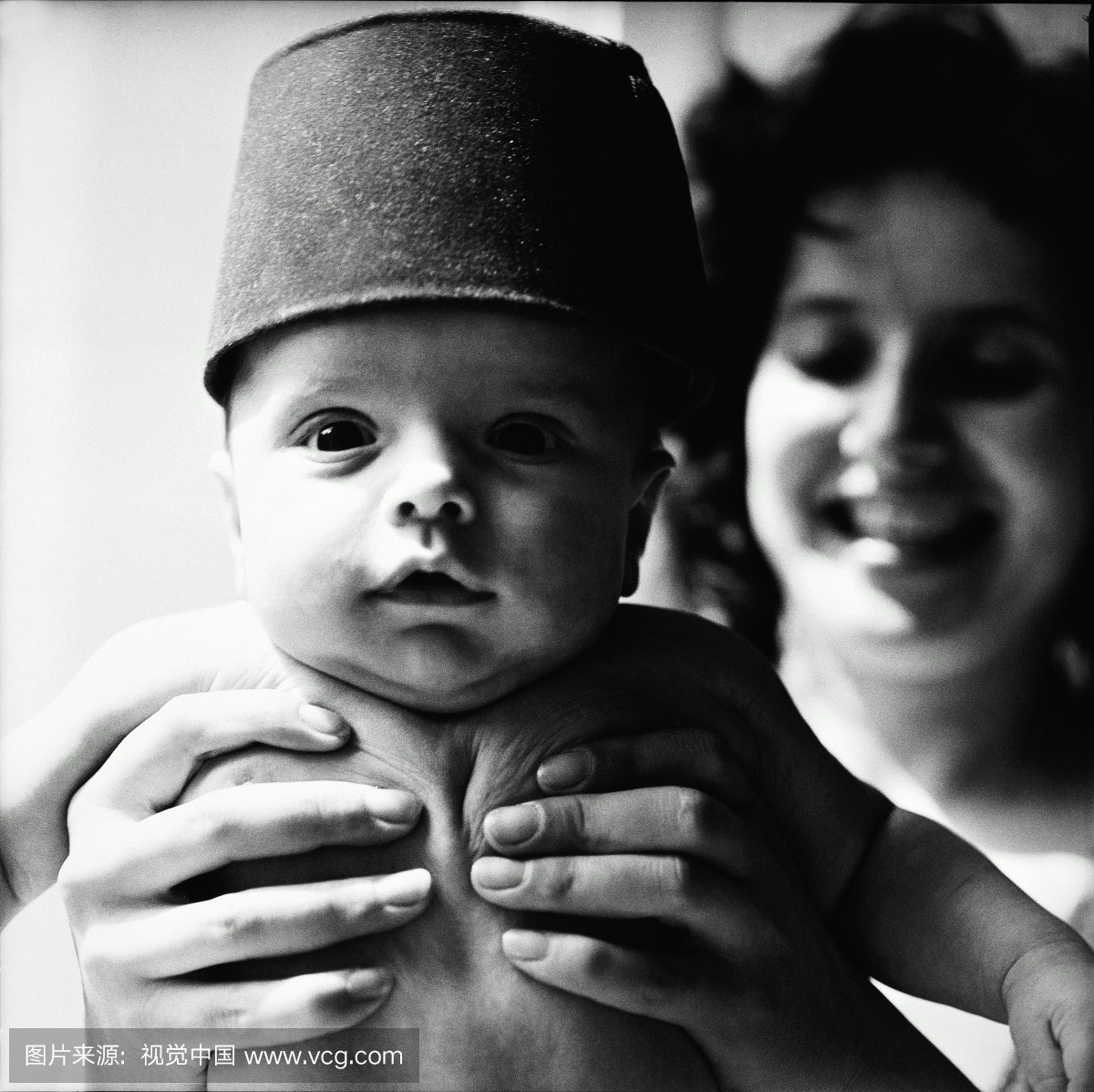母亲抱着婴儿(3-6个月)戴帽子,特写镜头(黑白)