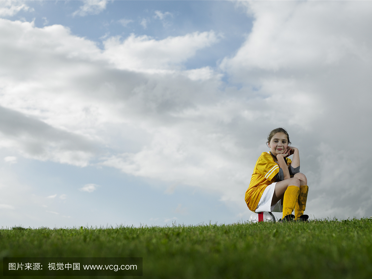 女孩(9-11)坐在足球上,休息下巴在手,肖像