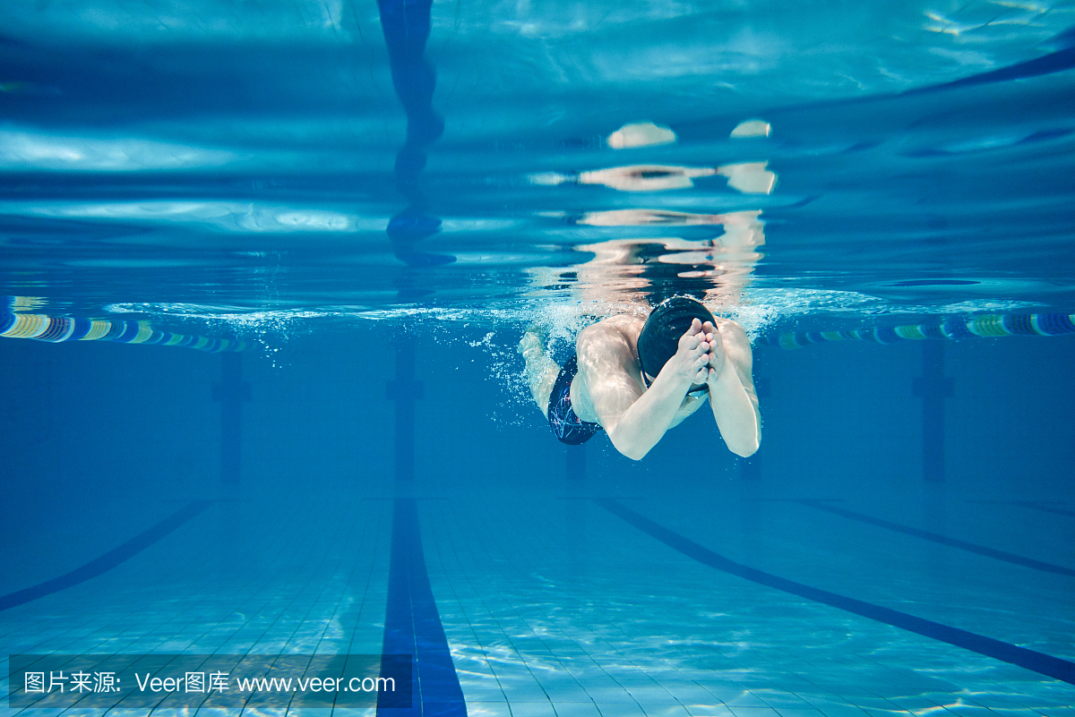 男游泳运动员在游泳池内水下游泳