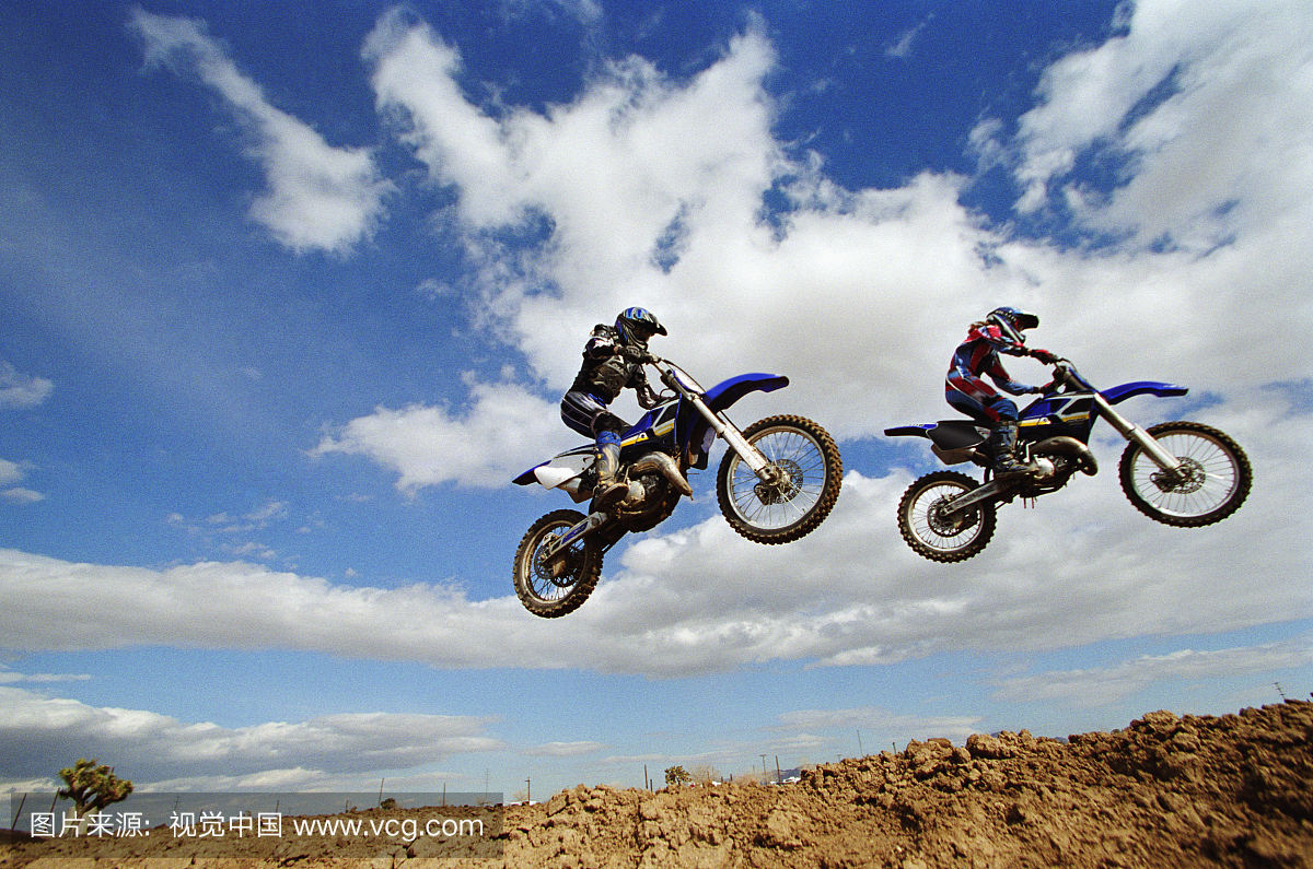 两只女越野摩托车手在空中,侧视图