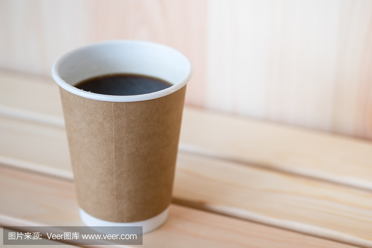 关闭热的黑咖啡美式纸杯在木桌上。