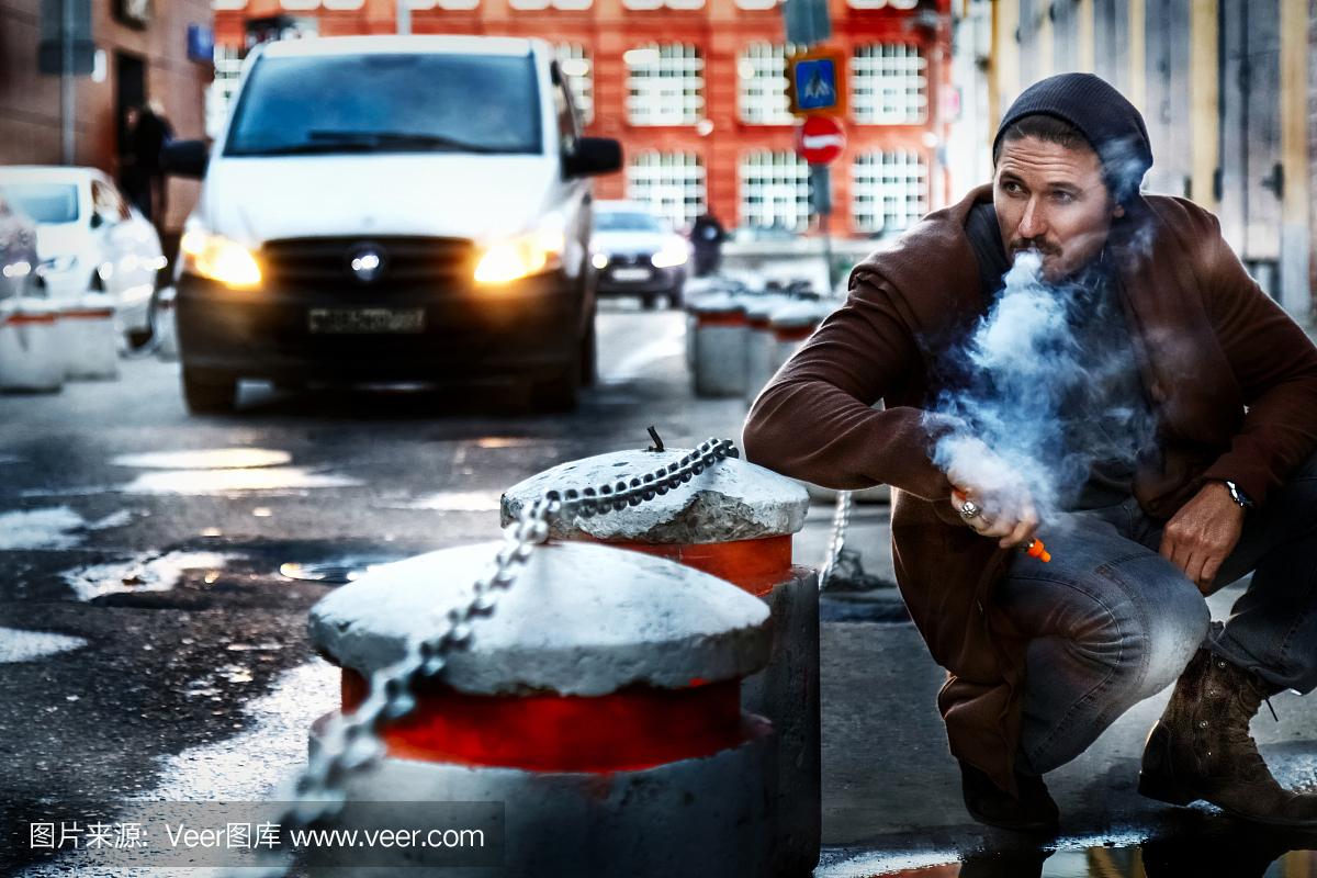 男子在大城市的街道上抽电子烟。
