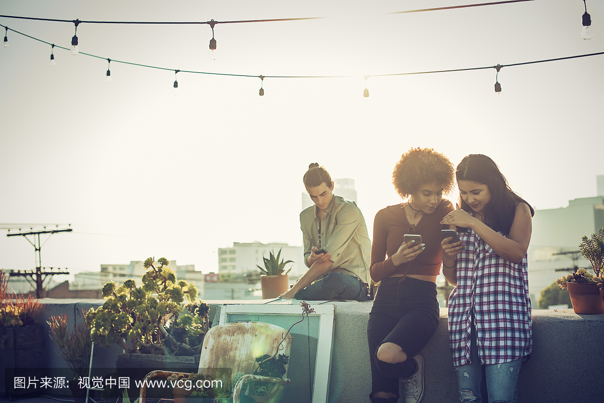 年轻的朋友在城市屋顶上检查智能手机
