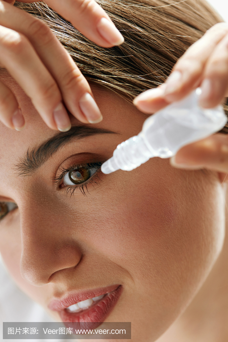 美丽的年轻女子在眼睛中应用眼药水。视觉概念