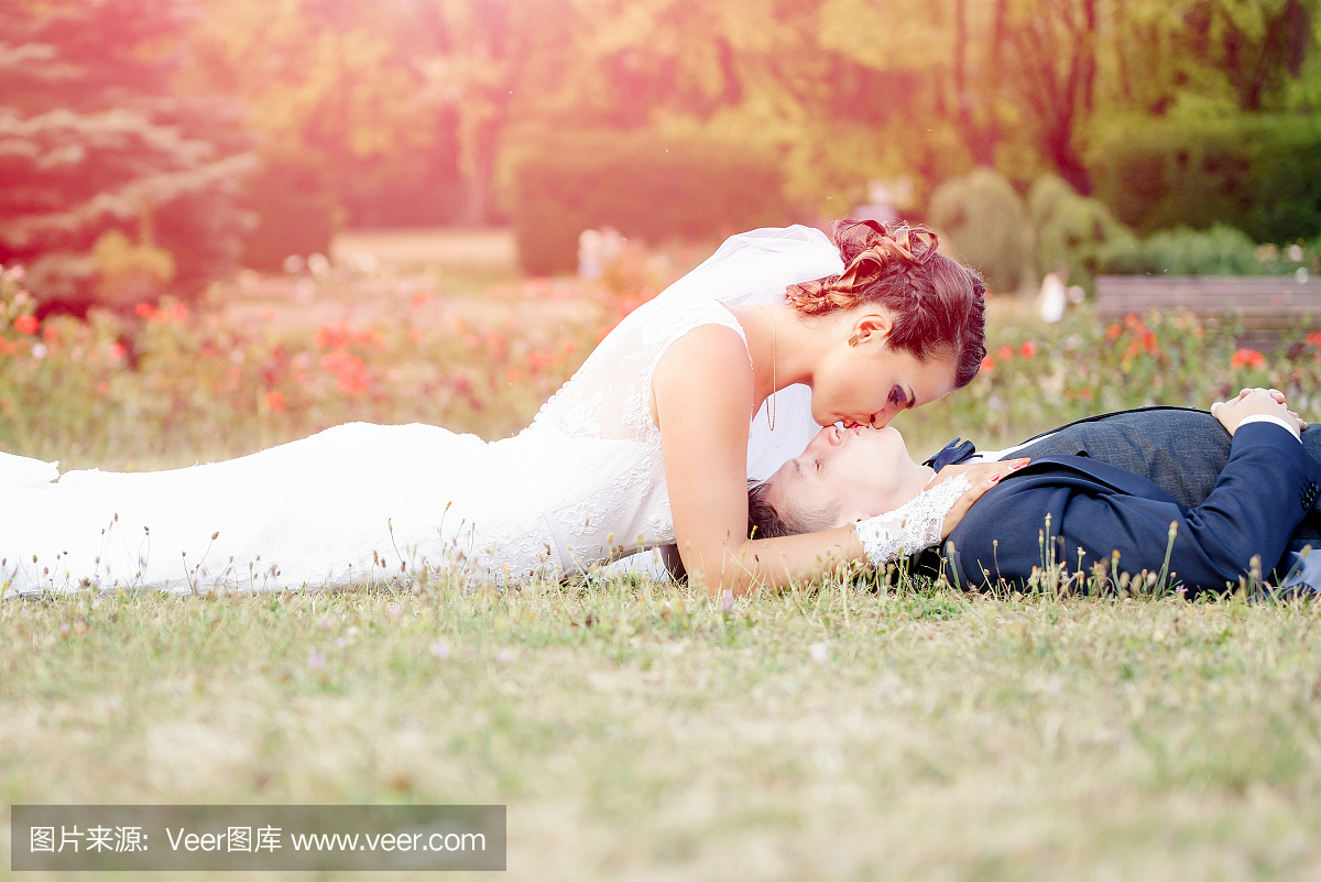 新娘亲吻在草地上躺着的新郎
