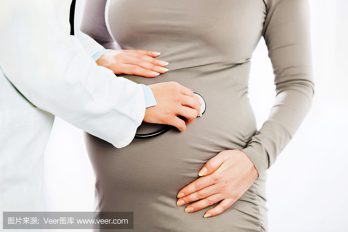 妇科医生用听诊器检查孕妇的腹部。