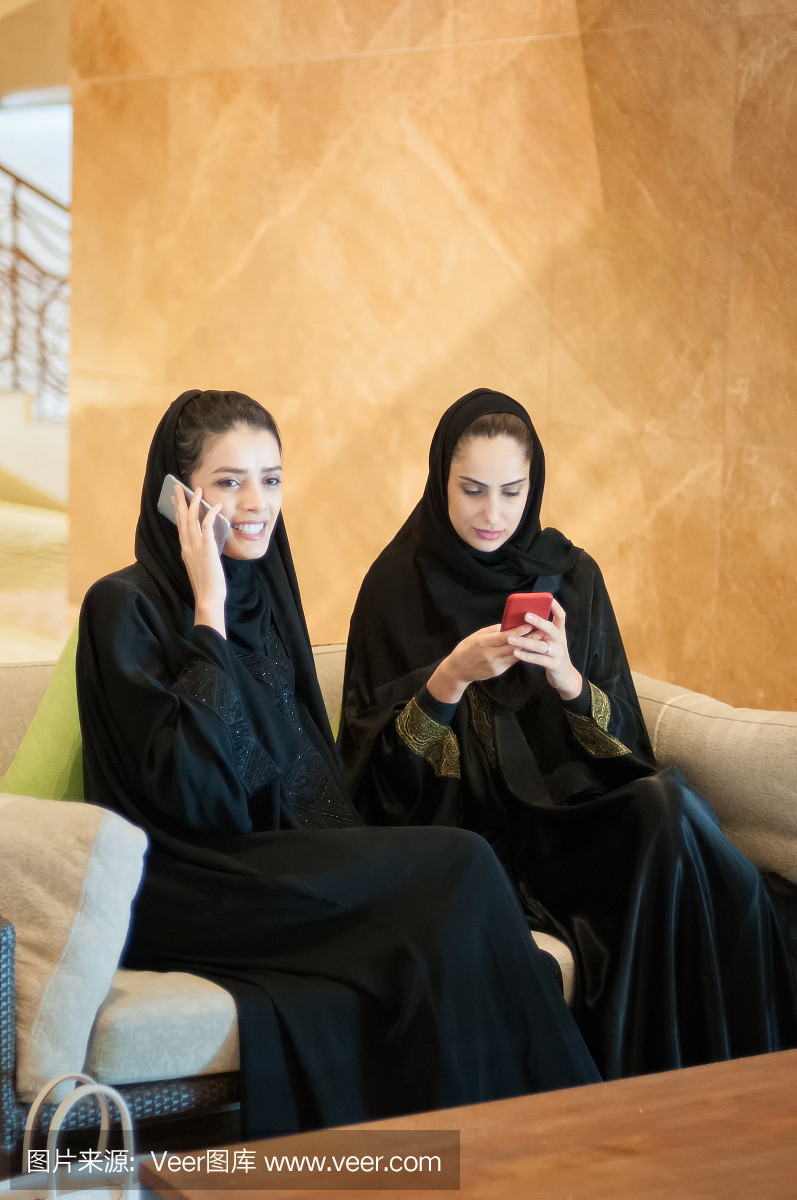中东妇女在手机上聊天和发短信,酒店大堂