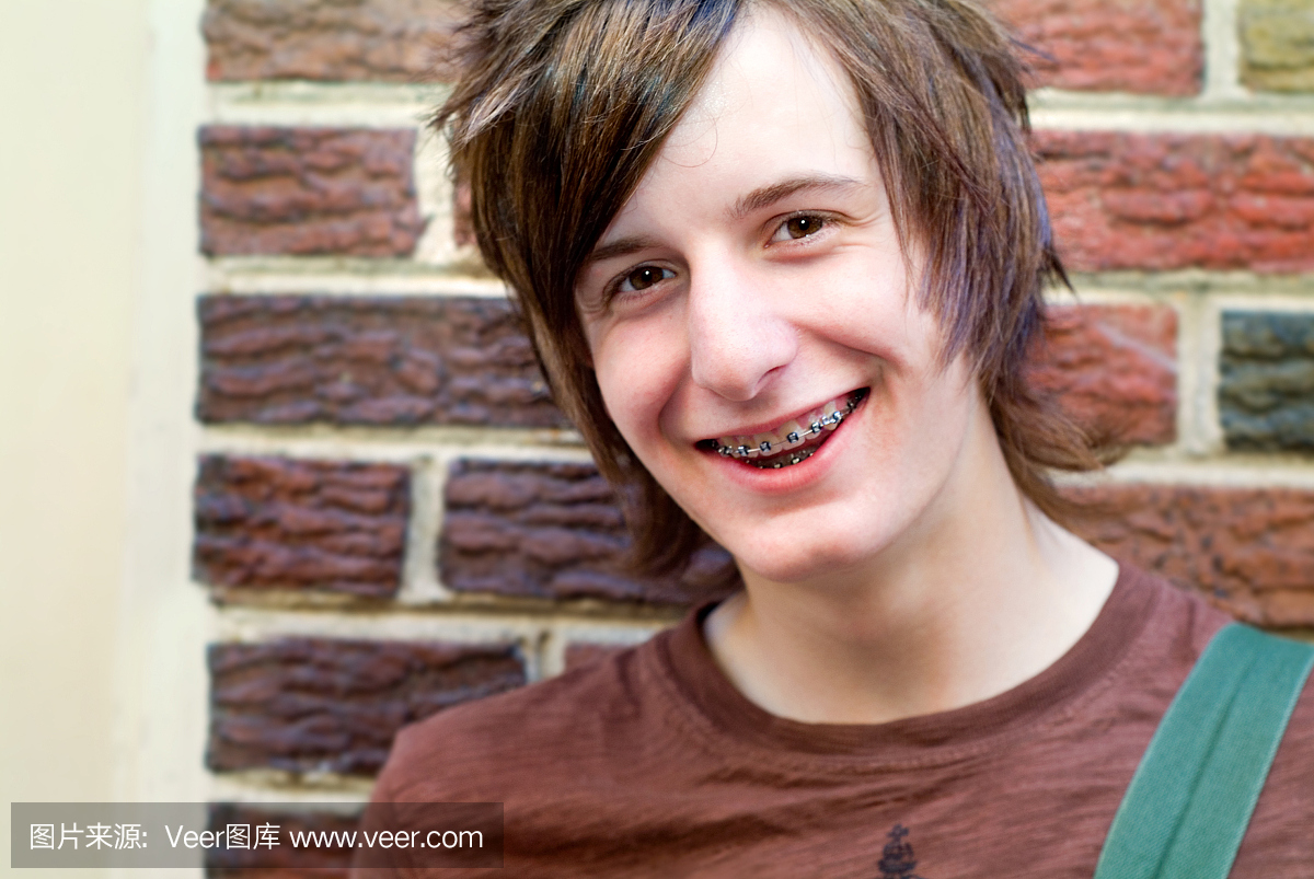 快乐的微笑男性青少年与他的牙齿上的大括号