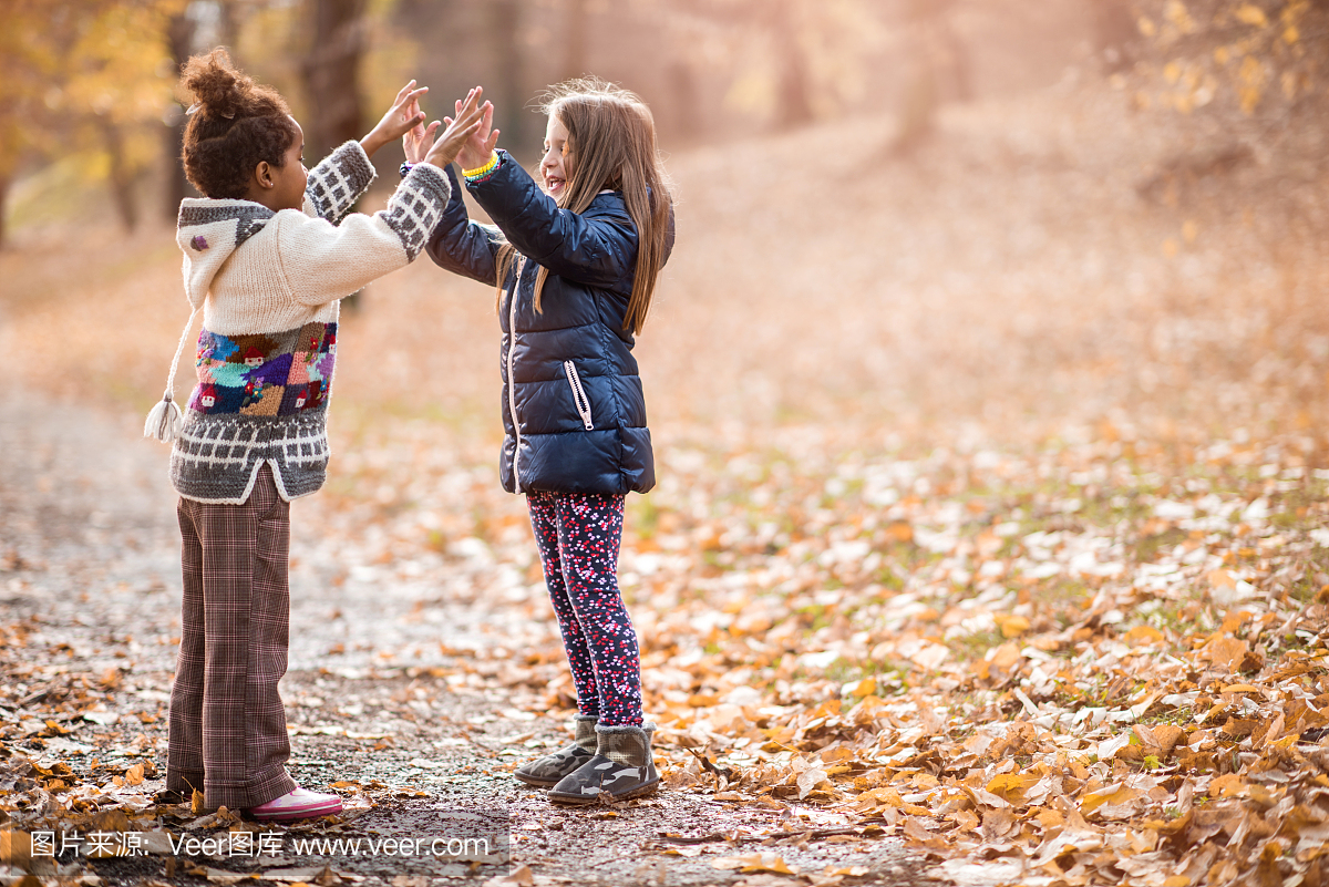 两个小女孩在公园里玩拍手游戏。
