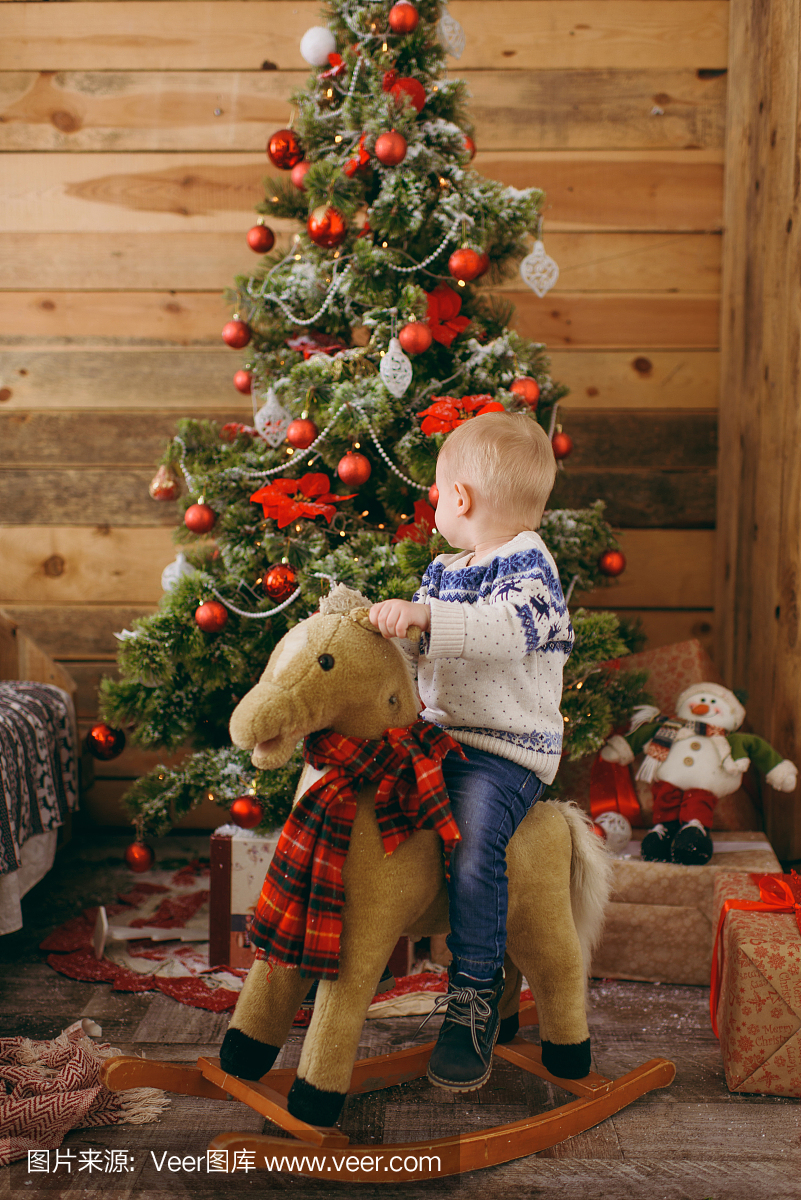 快乐可爱的小宝贝男孩在圣诞树上的玩具,穿着