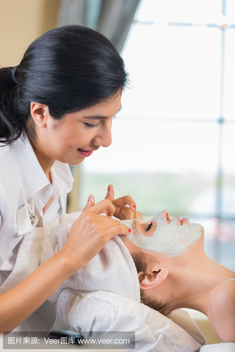 专业美容师在面部护理面膜时向客户使用面膜