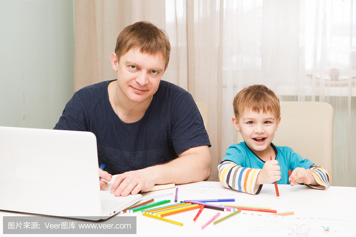 小男孩画画,而他的父亲正在一台笔记本电脑上