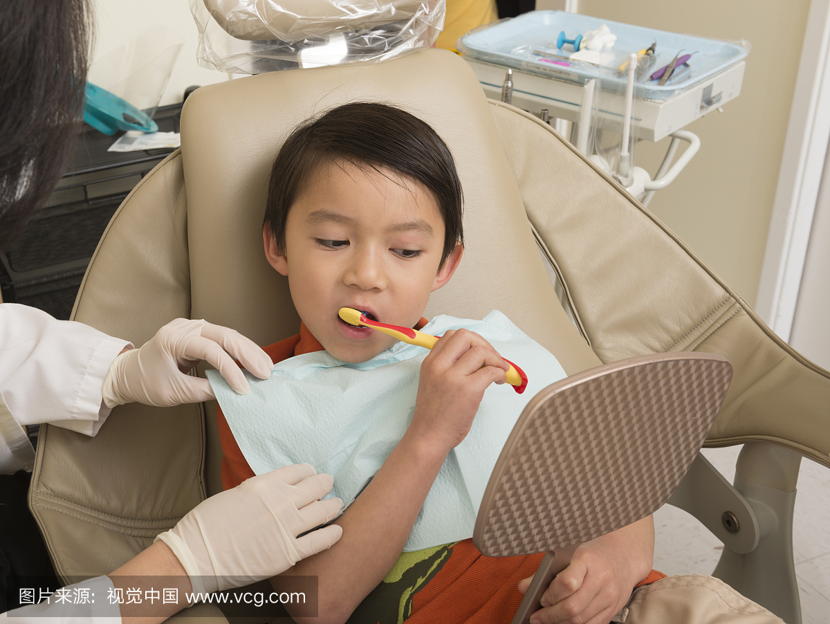 牙医椅上的小男孩学习如何刷牙