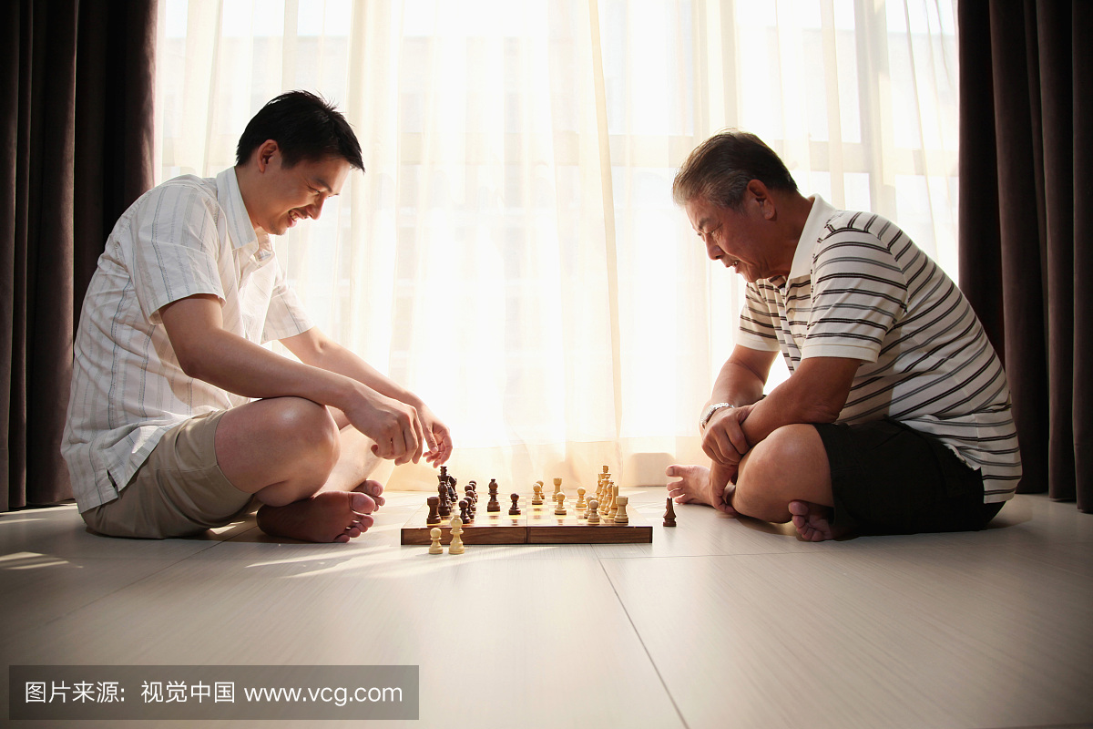 父亲和儿子在室内玩象棋游戏,全长,侧视图