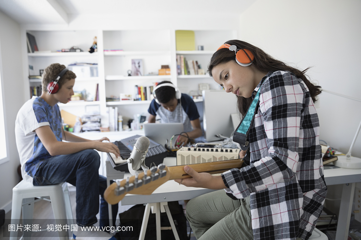 十几岁的女孩,戴着耳机弹电吉他,与朋友在家庭