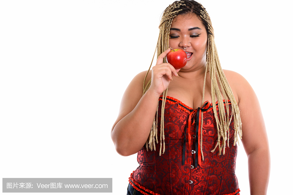 年轻快乐的胖亚洲女人微笑着吃红苹果