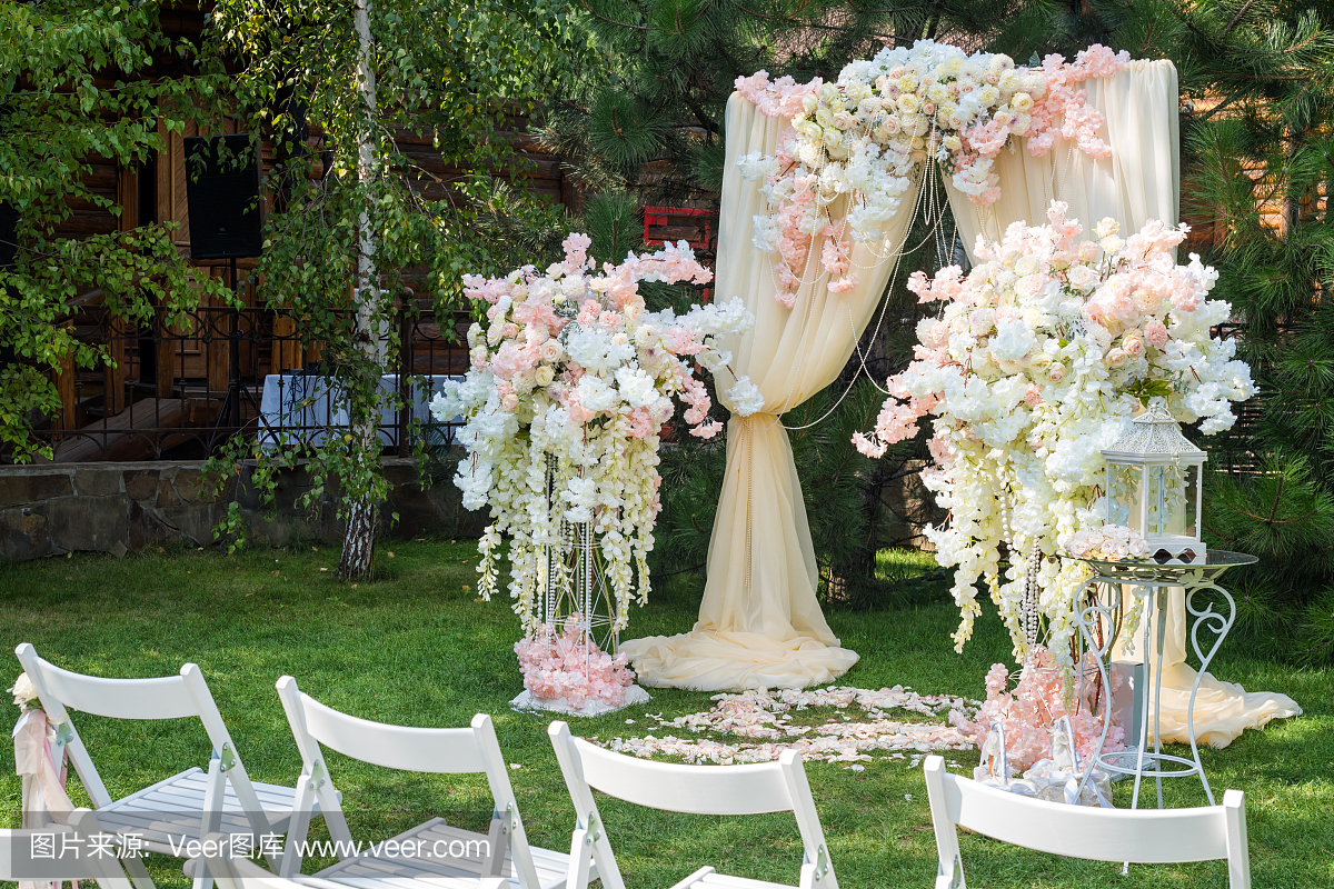 用布和花装饰的婚礼拱门户外。美丽的婚礼成立
