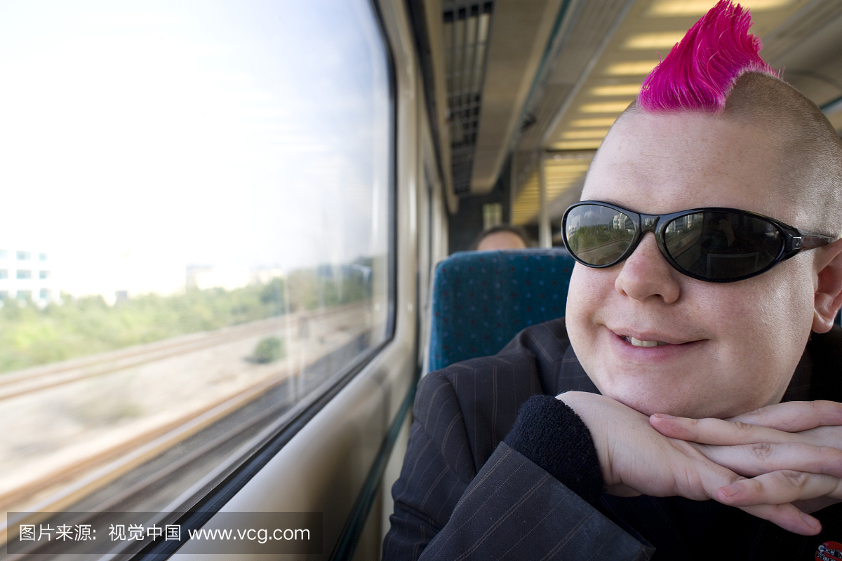 年轻人与粉红色的头发,在火车上看窗外